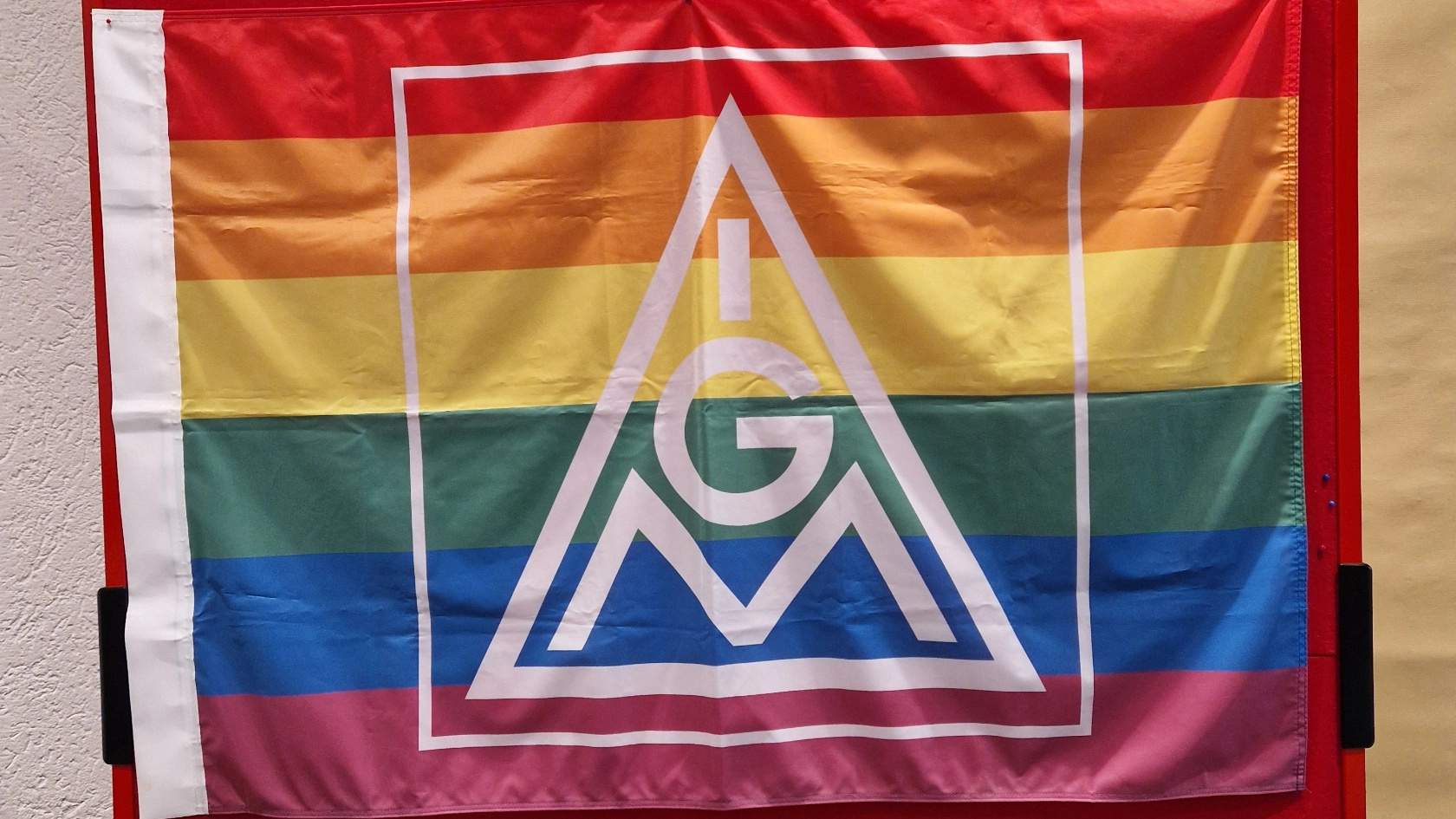 Das Bild zeigt eine Regenbogenflagge mit IG Metall-Logo.
