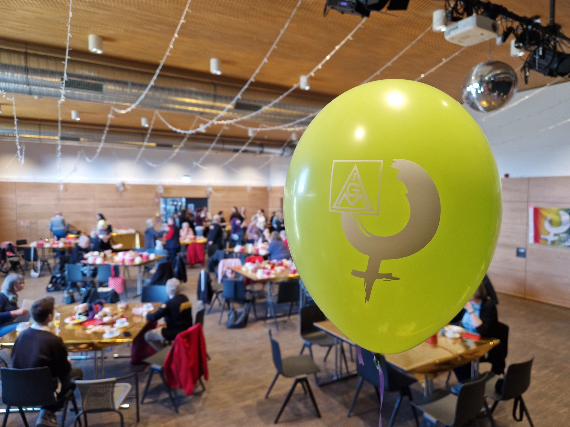 Unser Frauenfrühstück. Blick in den Raum mit einem gelben Ballon im Vordergrund mit einem Aufdruck des Frauenlogos.