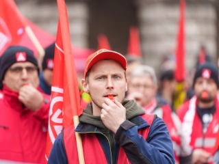 Ein junger Mann mit Trillerpfeife bei einem Warnstreik