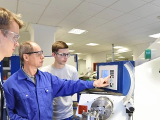 Junge Auszubildende werden an einer CNC-Maschine trainiert.